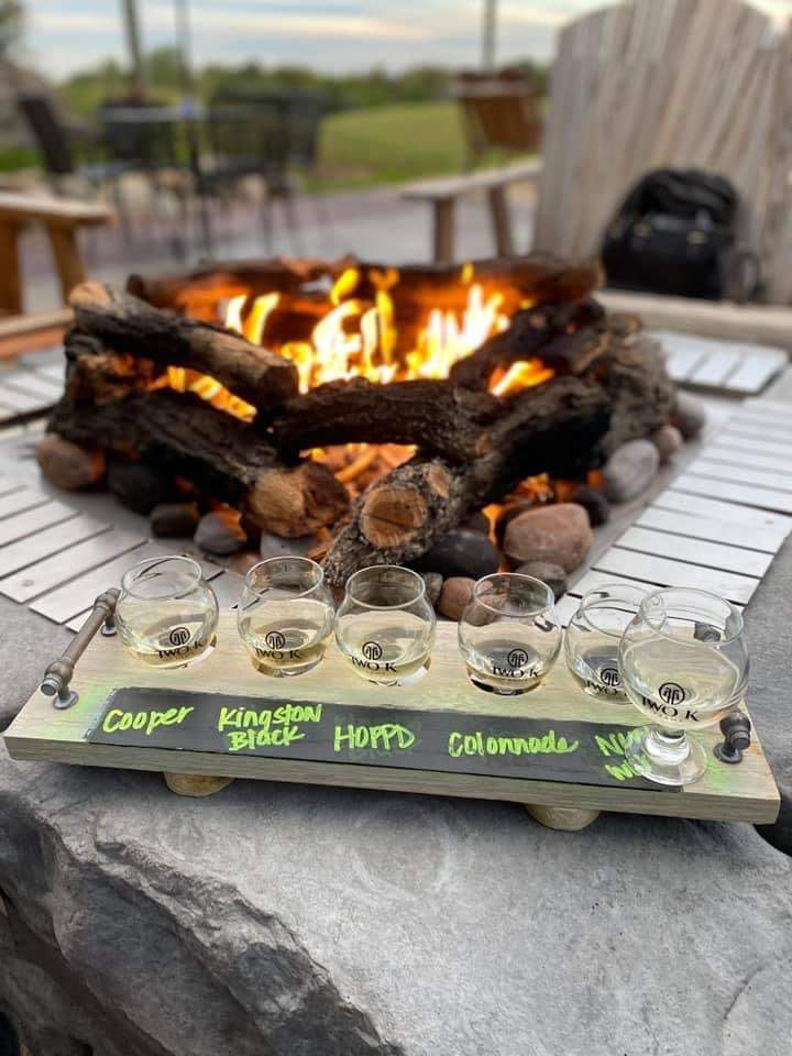 Photo of a Two K Farms cider flight sitting next to an outdoor fire.