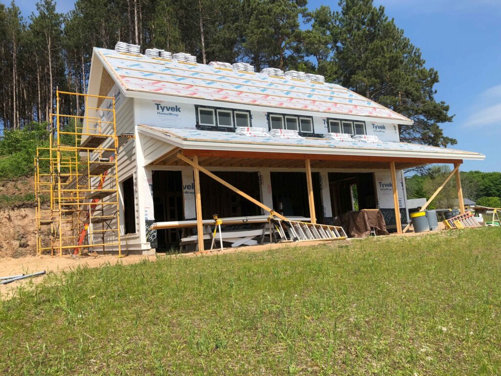 Exterior of the tasting room during construction. Building has scaffolding on the side, and bundles of shingles on the roof that are waiting to be installed.