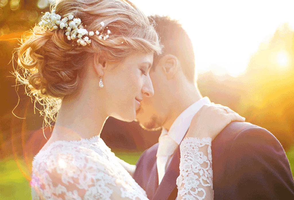 Photo of a bride and groom with the sun setting in the background.